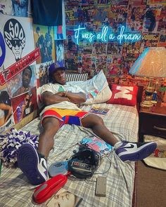 a man laying on top of a bed in a bedroom next to a wall with posters