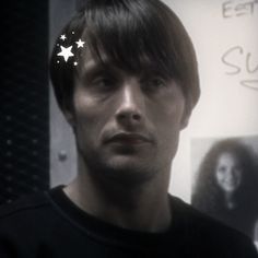 a man is staring at the camera with stars on his forehead and hair in front of him