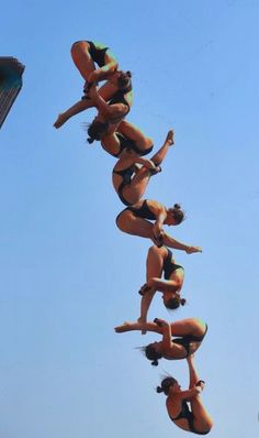 a group of women in bikinis doing tricks on a surfboard