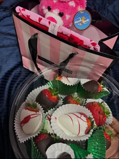 a pink teddy bear sitting next to some chocolate covered strawberries