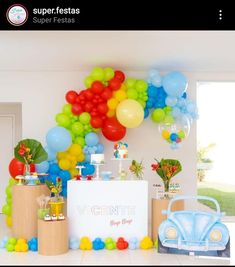 a table topped with lots of balloons next to a blue car and some wooden boxes