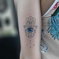 a woman's arm with a hamsa tattoo on it, and an evil eye