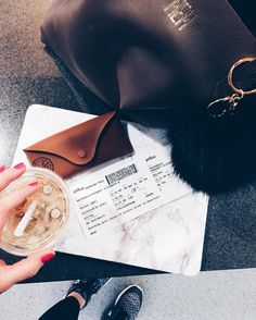 a woman holding a drink next to a purse on top of a marble countertop