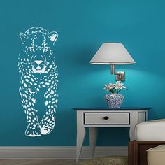 a blue wall with a white tiger decal next to a night stand and lamp