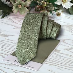 a green neck tie sitting on top of a table next to flowers and a card