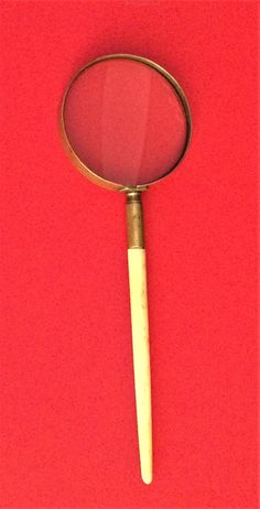 a magnifying glass sitting on top of a red table next to a yellow object