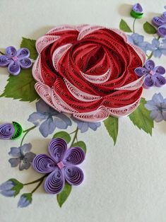 paper flowers are arranged on the table with purple and pink flowers in the center, along with green leaves