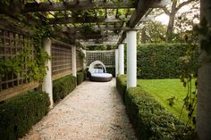 an outdoor area with hedges, bushes and a bed in the middle that is attached to a pergolated wall