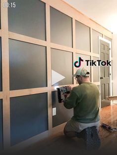 a man is working on the wall in his house with some paint and wood paneling