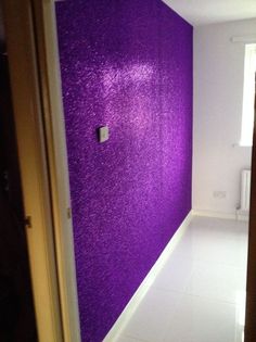 an empty room with a purple wall in the corner and white tile flooring on the walls