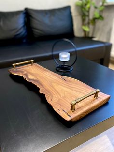 a wooden object sitting on top of a table next to a black couch in a living room