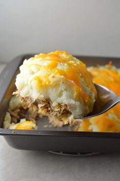 a casserole dish with meat and cheese on it is being eaten by a spoon