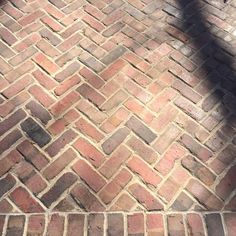 the shadow of a person standing on a brick walkway