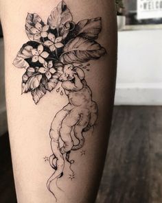 a woman's leg with flowers on it and an animal in the middle of her leg