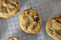 several chocolate chip cookies cooling on a wire rack, with one cookie in the middle