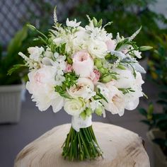 a bouquet of white and pink flowers sitting on top of a tree stump