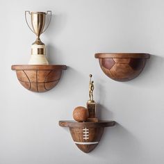 three wooden bowls and trophies are hanging on the wall