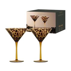 two champagne glasses with giraffe print in front of an open box on a white background