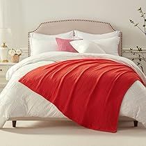 a bed with red and white comforters in a bedroom