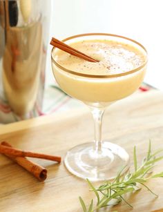 a drink in a glass with cinnamon sticks next to it and a box of golden eggnog