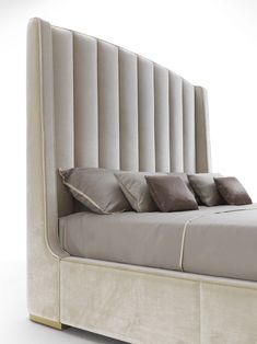 an upholstered bed with four pillows on it