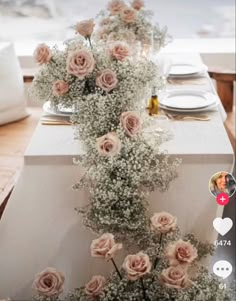 the table is set with pink roses and baby's breath