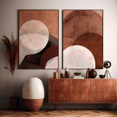 two abstract paintings hang on the wall next to a sideboard