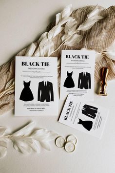 two black and white business cards sitting next to some feathers