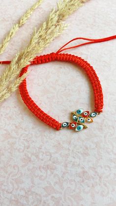 a red bracelet with two evil eyes on it and some wheat stalks in the background