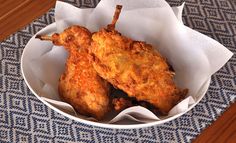 two fried chicken wings in a white bowl on a blue and white tableclothed placemat