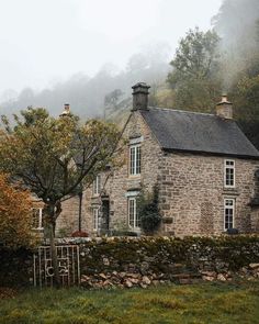 an old stone house surrounded by trees and fog