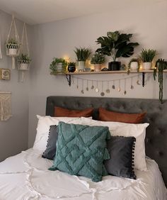 a bed with pillows and some plants on the headboard