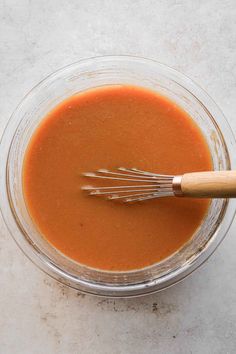 a glass bowl filled with sauce and whisks