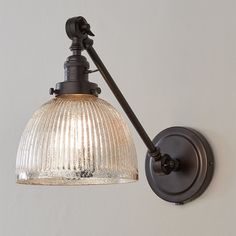 an old fashioned wall light with a glass shade on the side and black metal arm