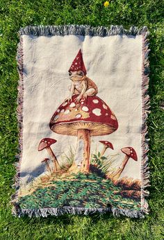 a mushroom with a gnome on it is sitting in the grass next to a throw blanket