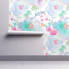 a white wall with blue and pink flowers on it next to a roll of toilet paper