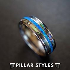 a ring with blue and green inlays is shown on a black table top