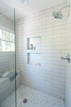 a white tiled bathroom with glass shower door