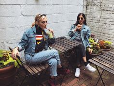 two women sitting at a picnic table drinking coffee