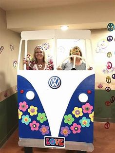 two girls in a vw bus with peace signs on the side and flowers painted on the front