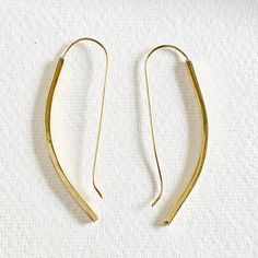 two pairs of gold - plated metal earrings on white background, one with curved ends