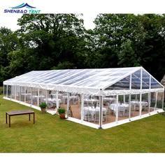 a large white tent set up in the middle of a field with tables and chairs