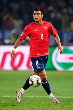 a soccer player in red and blue is kicking the ball down the field with his foot