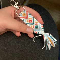 a hand holding a small piece of fabric with a keychain attached to it