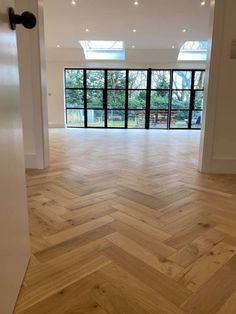 an empty room with wood flooring and large glass doors leading to the outside patio