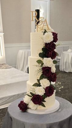 a three tiered wedding cake with white and red flowers