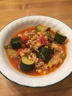 a white bowl filled with vegetable soup on top of a wooden table