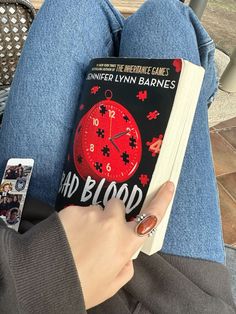 a person is holding a book with a clock on it and playing the game dead blood