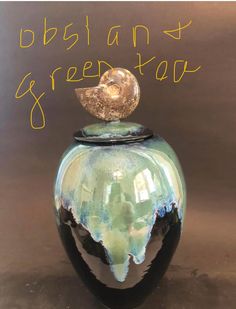 a green vase with a gold top sitting on a brown surface next to the words, obslan & greentop