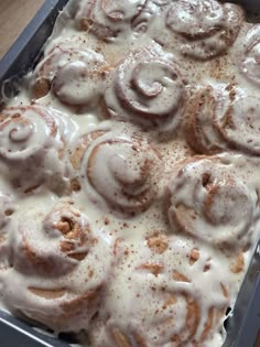 a pan filled with cinnamon rolls covered in icing